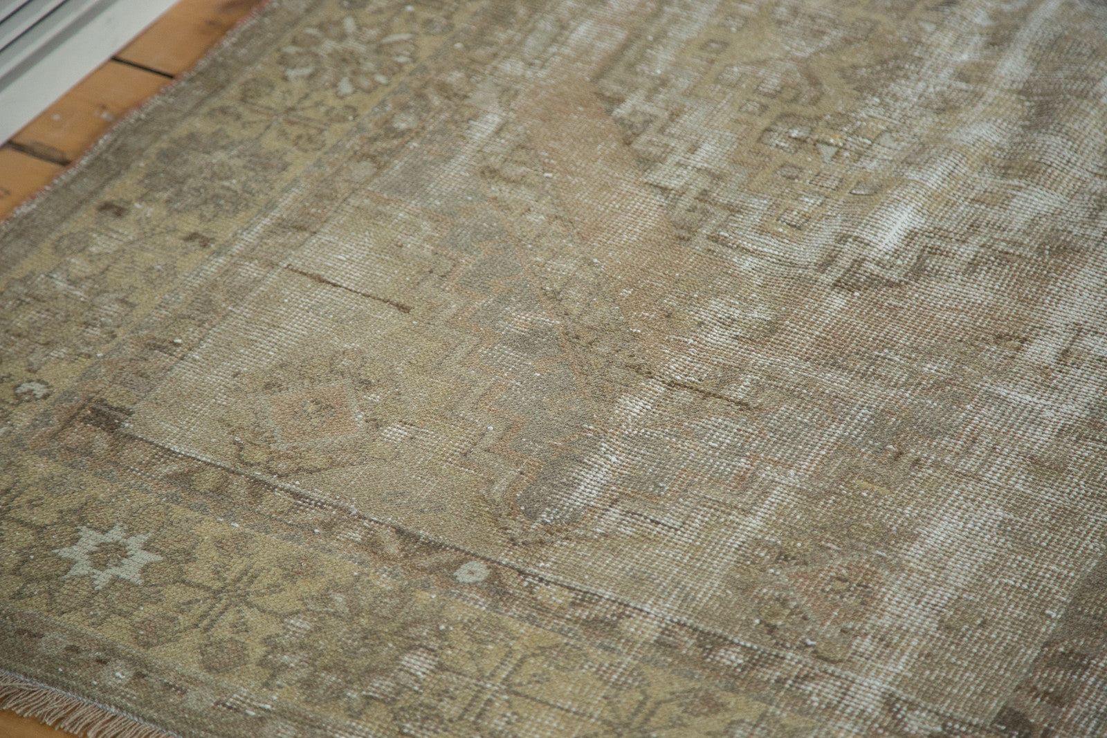 Distressed vintage Oushak rug texture, showing muted earth tones and geometric border pattern.